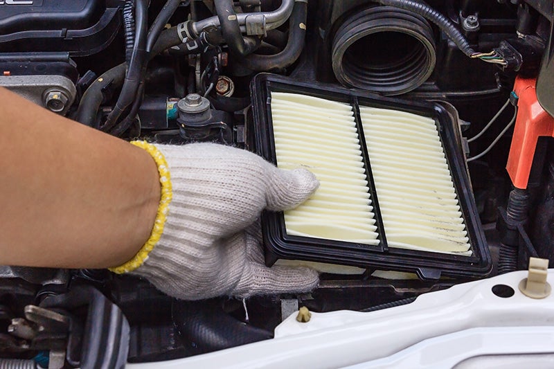 A professional Ford technician inspecting an air filter in a clean service bay in Lander, Wyoming.